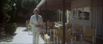 Movie still from “The Long Goodbye” (1973), directed by Robert Altman – A man in a white suit standing in front of a patio; Wide shot, Low angle