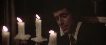 Movie still from “The Long Goodbye” (1973), directed by Robert Altman – A man in a suit and tie looking at two lit candles; Close Up shot, Over the shoulder angle