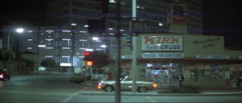 Movie still from “The Long Goodbye” (1973), directed by Robert Altman – A car driving down a street next to a traffic light at night; Extreme Wide shot, Low angle