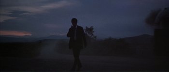 Movie still from “The Long Goodbye” (1973), directed by Robert Altman – A man in a suit and tie standing in the dark; Extreme Wide shot, Low angle