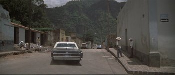 Movie still from “The Long Goodbye” (1973), directed by Robert Altman – A man walking down the street in front of an old car; Extreme Wide shot, Low angle
