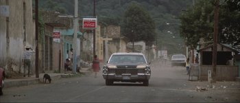 Movie still from “The Long Goodbye” (1973), directed by Robert Altman – A car driving down a street past a coca - cola sign; Extreme Wide shot, Low angle