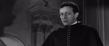 Movie still from “The Longest Day” (1962), directed by Ken Annakin – A black and white photo of a man in a priest's outfit; Close Up shot, Low angle