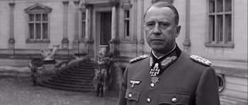 Movie still from “The Longest Day” (1962), directed by Ken Annakin – An older man in military uniform standing in front of a building; Close Up shot, Low angle