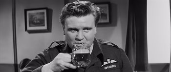 Movie still from “The Longest Day” (1962), directed by Ken Annakin – A man drinking a glass of beer while wearing an army uniform; Close Up shot, Low angle