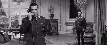Movie still from “The Longest Day” (1962), directed by Ken Annakin – A man in a uniform talking into a microphone; Medium shot, Over the shoulder angle