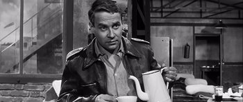 Movie still from “The Longest Day” (1962), directed by Ken Annakin – A black and white photo of a man holding a tea pot; Medium shot, High angle