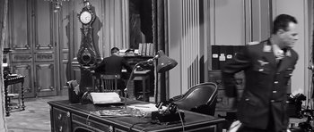 Movie still from “The Longest Day” (1962), directed by Ken Annakin – An office with a desk , chair , lamp , and other office equipment; Wide shot, High angle