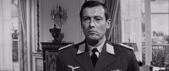 Movie still from “The Longest Day” (1962), directed by Ken Annakin – A man in a military uniform is looking at the camera; Close Up shot, Over the shoulder angle