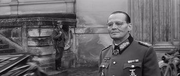 Movie still from “The Longest Day” (1962), directed by Ken Annakin – A man in a military uniform stands in front of a soldier; Medium shot, Low angle