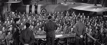 Movie still from “The Longest Day” (1962), directed by Ken Annakin – A group of men sitting in front of an airplane; Wide shot, High angle