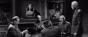 Movie still from “The Longest Day” (1962), directed by Ken Annakin – A group of men sitting around a table; Medium shot, Over the shoulder angle