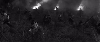Movie still from “The Longest Day” (1962), directed by Ken Annakin – A group of men in a field with smoke billowing out of them; Medium shot, Low angle