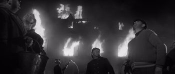 Movie still from “The Longest Day” (1962), directed by Ken Annakin – Many fire fighters that are standing in front of a building; Medium shot, Low angle