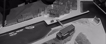 Movie still from “The Longest Day” (1962), directed by Ken Annakin – An aerial view of a city with a boat in the water; Extreme Wide shot, High angle