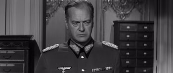 Movie still from “The Longest Day” (1962), directed by Ken Annakin – An old photo of a man in a military uniform; Close Up shot, Over the shoulder angle