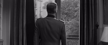 Movie still from “The Longest Day” (1962), directed by Ken Annakin – A black and white photo of a man looking out of a window; Medium shot, Low angle