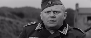 Movie still from “The Longest Day” (1962), directed by Ken Annakin – An older man in a military uniform stares at the camera; Close Up shot, Low angle