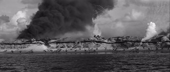 Movie still from “The Longest Day” (1962), directed by Ken Annakin – A black and white photo of an ocean and a beach; Extreme Wide shot, High angle