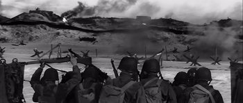 Movie still from “The Longest Day” (1962), directed by Ken Annakin – A black and white photo of a group of men in military gear; Wide shot, Low angle