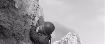 Movie still from “The Longest Day” (1962), directed by Ken Annakin – A man climbing a rock wall with a helmet on; Extreme Close Up shot, Low angle