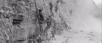 Movie still from “The Longest Day” (1962), directed by Ken Annakin – A black and white photo of a group of soldiers climbing a mountain; Extreme Wide shot, High angle