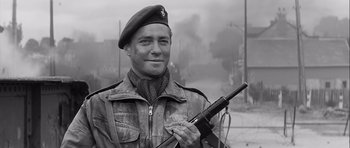 Movie still from “The Longest Day” (1962), directed by Ken Annakin – A man in a military uniform holding a gun; Close Up shot, Low angle