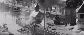 Movie still from “The Longest Day” (1962), directed by Ken Annakin – An old photo of a street with a church and a bridge in the background; Extreme Wide shot, High angle
