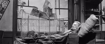 Movie still from “The Longest Day” (1962), directed by Ken Annakin – An older man sitting in a chair in front of a window; Wide shot, Low angle