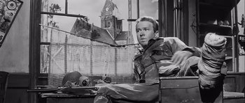 Movie still from “The Longest Day” (1962), directed by Ken Annakin – Black and white photograph of a man sitting on a bench; Medium shot, Low angle