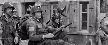 Movie still from “The Longest Day” (1962), directed by Ken Annakin – Two men sitting next to each other holding guns; Medium shot, Over the shoulder angle