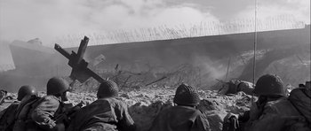 Movie still from “The Longest Day” (1962), directed by Ken Annakin – Two men are sitting in the sand looking at a wall; Extreme Wide shot, Low angle