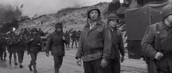 Movie still from “The Longest Day” (1962), directed by Ken Annakin – A group of men standing next to each other on top of a hill; Medium shot, Low angle
