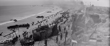 Movie still from “The Longest Day” (1962), directed by Ken Annakin – An aerial view of a beach with military vehicles on it and barbed wire; Extreme Wide shot, High angle