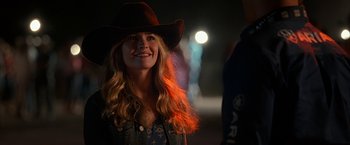 Movie still from “The Longest Ride” (2015), directed by George Tillman Jr. – A woman wearing a cowboy hat smiling for the camera; Close Up shot, Over the shoulder angle