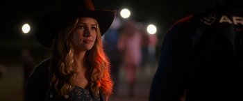 Movie still from “The Longest Ride” (2015), directed by George Tillman Jr. – A woman in a cowboy hat is standing in front of a crowd; Close Up shot, Over the shoulder angle