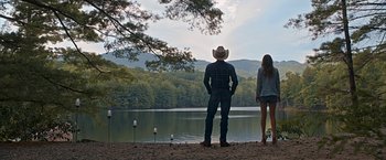 Movie still from “The Longest Ride” (2015), directed by George Tillman Jr. – A man and a woman standing next to a lake; Wide shot, Low angle