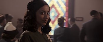 Movie still from “The Longest Ride” (2015), directed by George Tillman Jr. – A young woman with dark brown hair standing in front of a stained glass window; Close Up shot, Over the shoulder angle