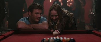 Movie still from “The Longest Ride” (2015), directed by George Tillman Jr. – A man and a woman leaning over a pool table to look at a ball; Medium shot, Over the shoulder angle