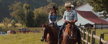 Movie still from “The Longest Ride” (2015), directed by George Tillman Jr. – A man and a woman riding horses in a field; Medium shot, Over the shoulder angle