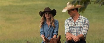 Movie still from “The Longest Ride” (2015), directed by George Tillman Jr. – A man and a woman wearing cowboy hats on a horse; Medium shot, Over the shoulder angle