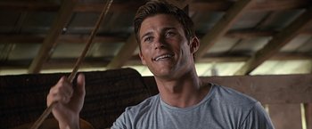 Movie still from “The Longest Ride” (2015), directed by George Tillman Jr. – A person wearing a gray t - shirt smiling; Close Up shot, Over the shoulder angle