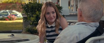Movie still from “The Longest Ride” (2015), directed by George Tillman Jr. – A woman sitting on top of a chair in a yard; Close Up shot, Over the shoulder angle
