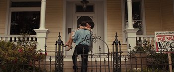 Movie still from “The Longest Ride” (2015), directed by George Tillman Jr. – A man holding a woman in front of a house; Wide shot, Low angle