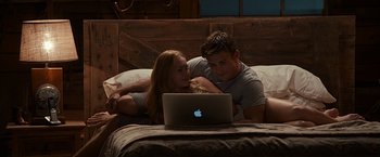 Movie still from “The Longest Ride” (2015), directed by George Tillman Jr. – A man and a woman laying in a bed looking at a laptop computer; Wide shot, High angle