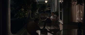Movie still from “The Longest Ride” (2015), directed by George Tillman Jr. – A man sitting on top of a chair on top of a porch; Wide shot, High angle