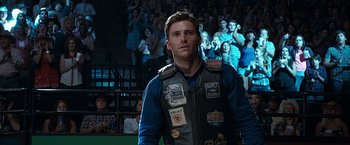 Movie still from “The Longest Ride” (2015), directed by George Tillman Jr. – A man in a leather jacket stands in front of an audience; Close Up shot, Over the shoulder angle