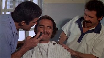 Movie still from “The Longest Yard” (1974), directed by Robert Aldrich – A man getting his mustache shaved by two men; Close Up shot, Over the shoulder angle