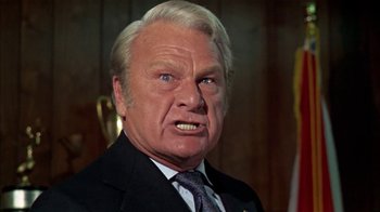 Movie still from “The Longest Yard” (1974), directed by Robert Aldrich – An older man in a suit and tie; Close Up shot, Low angle