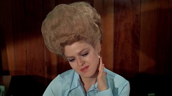 Movie still from “The Longest Yard” (1974), directed by Robert Aldrich – A woman with a huge hair piece on her head; Close Up shot, Low angle
